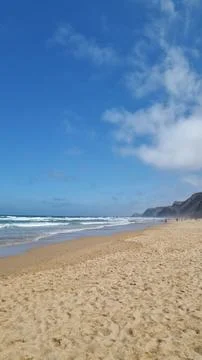 Wide view of a sandy Atlantic beach framed by coastal dunes and beach umbrell Stock Photos