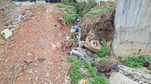 Wide view of a small drain overflowing heavily polluted water with garbage .. Video stock 336624770