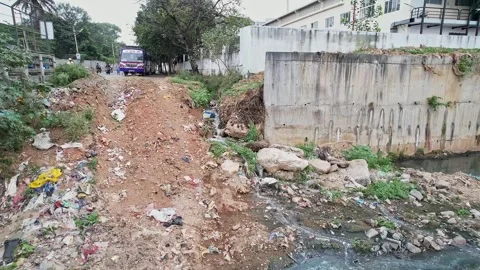 Wide view of a small drain overflowing heavily polluted water with garbage .. Video stock 336624773