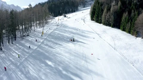 A wide view of a snow-covered ski slope with scattered skiers gliding down Stock Footage 285900623