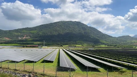 Wide view of solar panel arrays covering open land, with mountains and cloudy Stock Footage 327725582