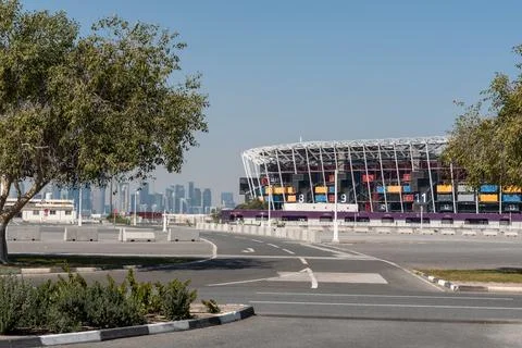 Wide view of Stadium 974 framed by trees across a paved road in Ras Abu Aboud. Stock Photos
