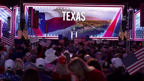 Wide view of the stage with a 'Texas' backdrop as delegates wave flags Stock Footage 345271531