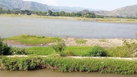 Wide View of Swat River Flowing Through Green Grass With Mountains Stock Footage 344856602