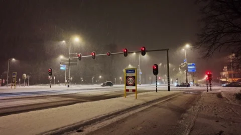 Wide view of traffic lights on an intersection on a snow winter night in Soest Stock Footage 326342894