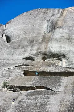 Wide view of two climbers on a massive vertical conglomerate rock tower under Stock Photos