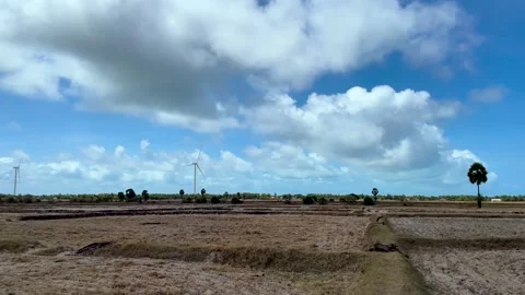 Wide view of uncultivated field with wind turbines in the distance. Stock Footage 290995994