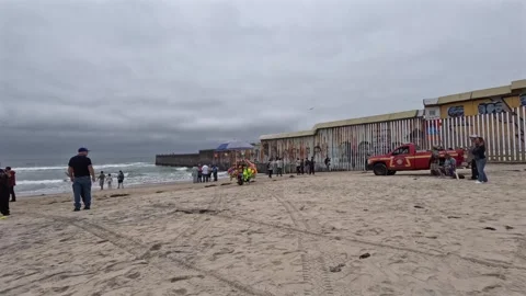 Wide view of the U.S.-Mexico border wall extending into the Pacific Ocean at Stock Footage 337724572