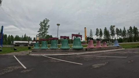 Wide view of Vaskikello bell collection display with passing truck on highway Stock Footage 340332921