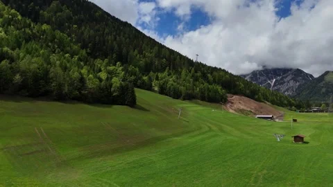 Wide View of Vibrant Green Slope Opening to Forested Mountain Ridge Stock Footage 342783929