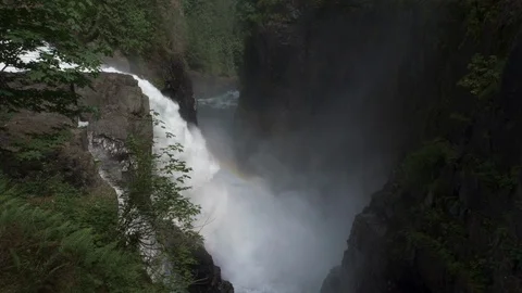 Wide view of waterfall surrounded by rocks and thick vegetation Stock Footage 119156725