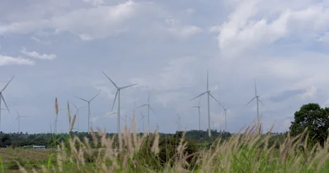 Wide view with wind turbines spinning over countryside field beneath blue cloudy Stock Footage 337161637
