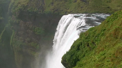 Wide on waterfall crest with vegetation, pan left and tilt down Stock Footage 37586377