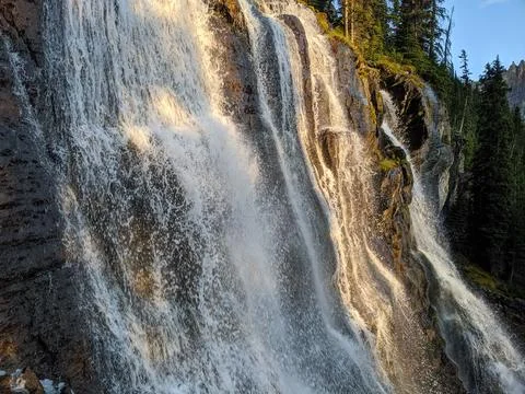 A wide waterfall flows over steep rocks Stock Photos