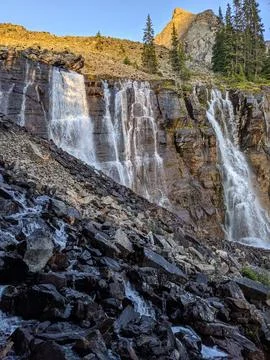A wide waterfall flows over steep rocks Stock Photos