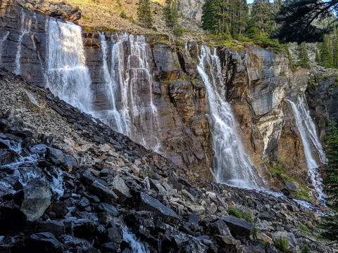 A wide waterfall flows over steep rocks Stock Photos