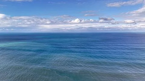 Wideangle aerial scene capturing tranquil sea surface beneath clear blue sk.. Photos