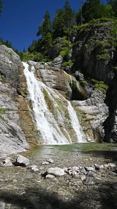 Wideangle vertical shot of a waterfall with its pond in the foreground, slow-mo Video stock 260878526