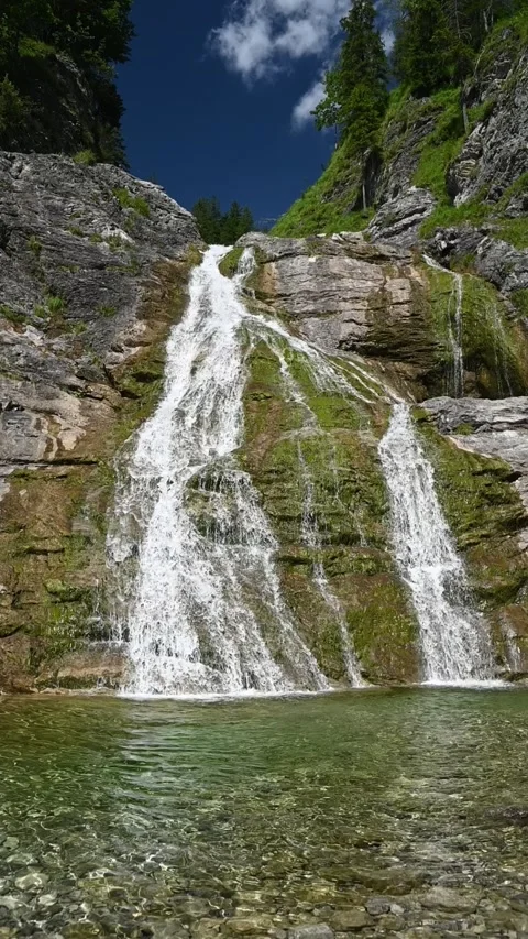 Wideangle vertical shot of a waterfall in the mountains in summer, slow motion Video stock 260875169