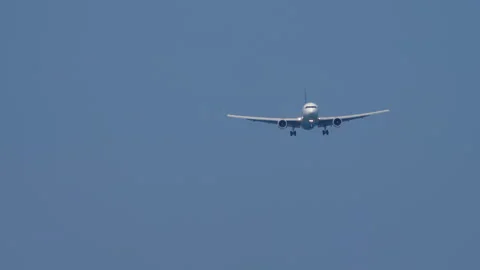 Widebody passenger airplane on final approach in clear blue sky Stock Footage 346983823