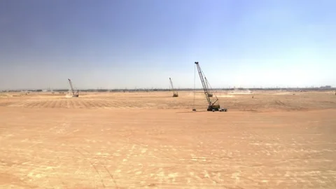 Widely spaced cranes across an open sandy construction site 库存影片 346430437