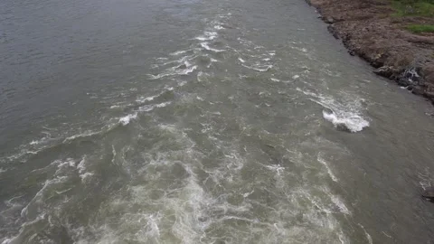 A widening trail of churning river rapids and white foam flowing rapidly downstr Stock Footage 342477374