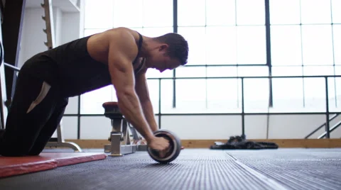 Wider view of strong young man using an ab roller in the gym, in slow motion Stock Footage 59745783