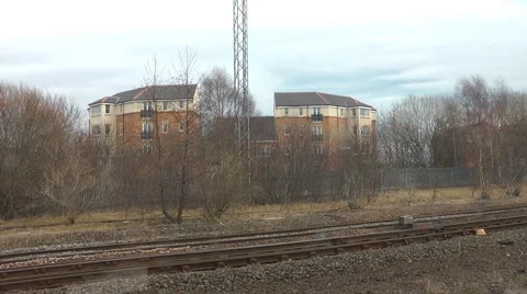 From widow of a train as it leaves a station in city suburbs and picks up speed Stock-Footage 1099929