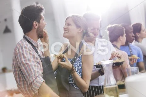 Wife feeding husband in cooking class kitchen Stock Photos