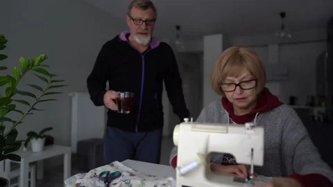 Wife scribbles on a sewing machine, the husband brings her tea with lemon. Happy Stock Footage 148679139