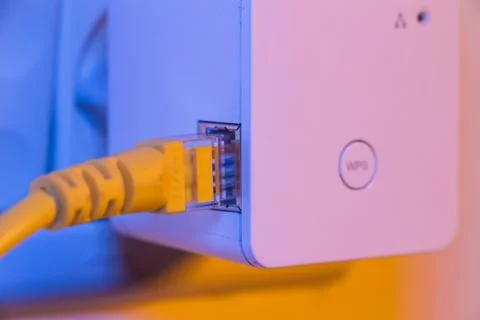 WiFi extender in electrical socket on the wall with ethernet cable plugged in Stock Photos
