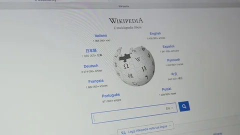Wikipedia Website's homepage on Laptop screen. Wikipedia logo. Stock Footage