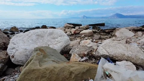 Wild Beach with Rocks and Plastic Garbage Pollution Visible Stock Footage 306312029