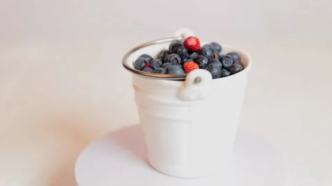 Wild berries in a white bucket on a light background. Stock Footage 224710286