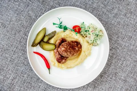 Wild boar cutlets with mashed potatoes. Served on a white plate with pickled Stock Photos