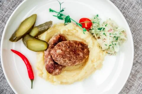 Wild boar cutlets with mashed potatoes. Served on a white plate with pickled Stock Photos