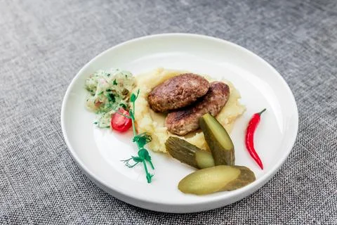 Wild boar cutlets with mashed potatoes. Served on a white plate with pickled Stock Photos