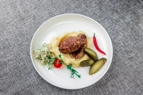 Wild boar cutlets with mashed potatoes. Served on a white plate with pickled Stock Photos