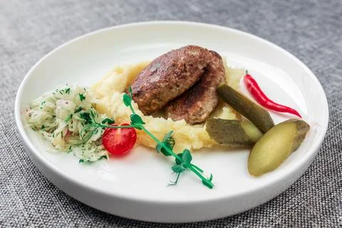Wild boar cutlets with mashed potatoes. Served on a white plate with pickled Stock Photos