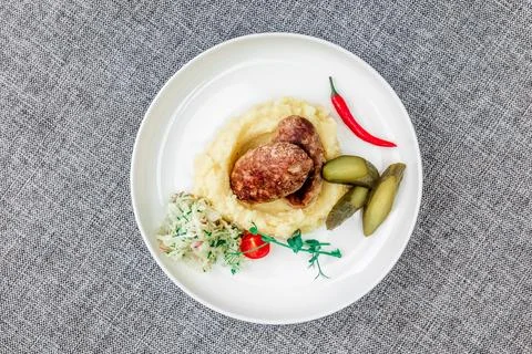 Wild boar cutlets with mashed potatoes. Served on a white plate with pickled Stock Photos