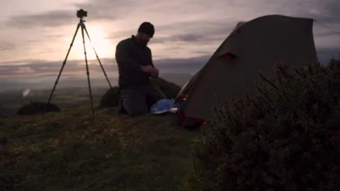 A wild camping photographer doing something beside a tent and camera tripod Vidéo 263967601