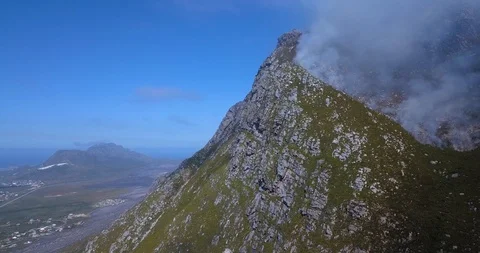 Wild fire spreading up a mountain peak in strong winds, DRONE, PAN RIGHT Stock Footage 100803231