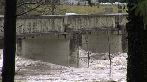 Wild flooding brown river running under the bridge with cars driving Stock Footage 105872768
