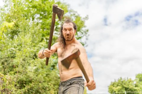 Wild man with bared torso with two axes Stock Photos