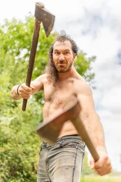 Wild man looking at camera while holding two axes Stock Photos
