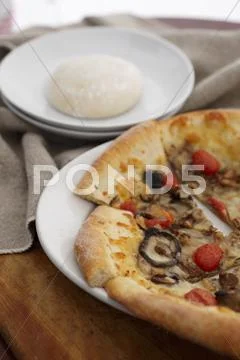 Wild Mushroom and Tomato Pizza; Sliced on a White Plate; Pizza Dough Stock Photos
