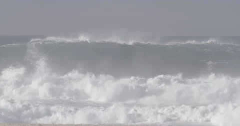Wild ocean waves splashing and breaking on sandy beach on sunny day in Nazare Stock Footage 160759923