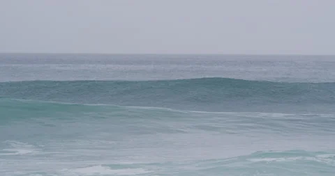 Wild ocean waves splashing in ocean with surfer sitting on surfboard near them Video stock 156011359