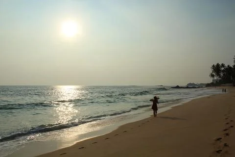 Wild raw empty beach in Sri Lanka with a girl wearing red dress Stock Photos