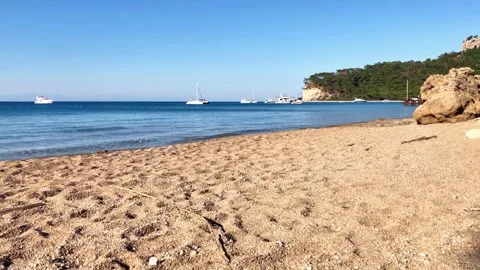 Wild sandy beach with waves, rocks and distant yachts – 4K 60fps Stock-Footage 328231126
